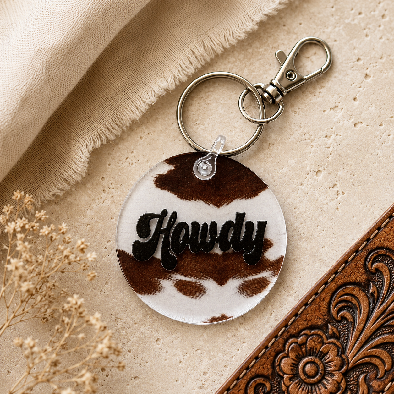 Keychain with 'Howdy' text on a cow print background
