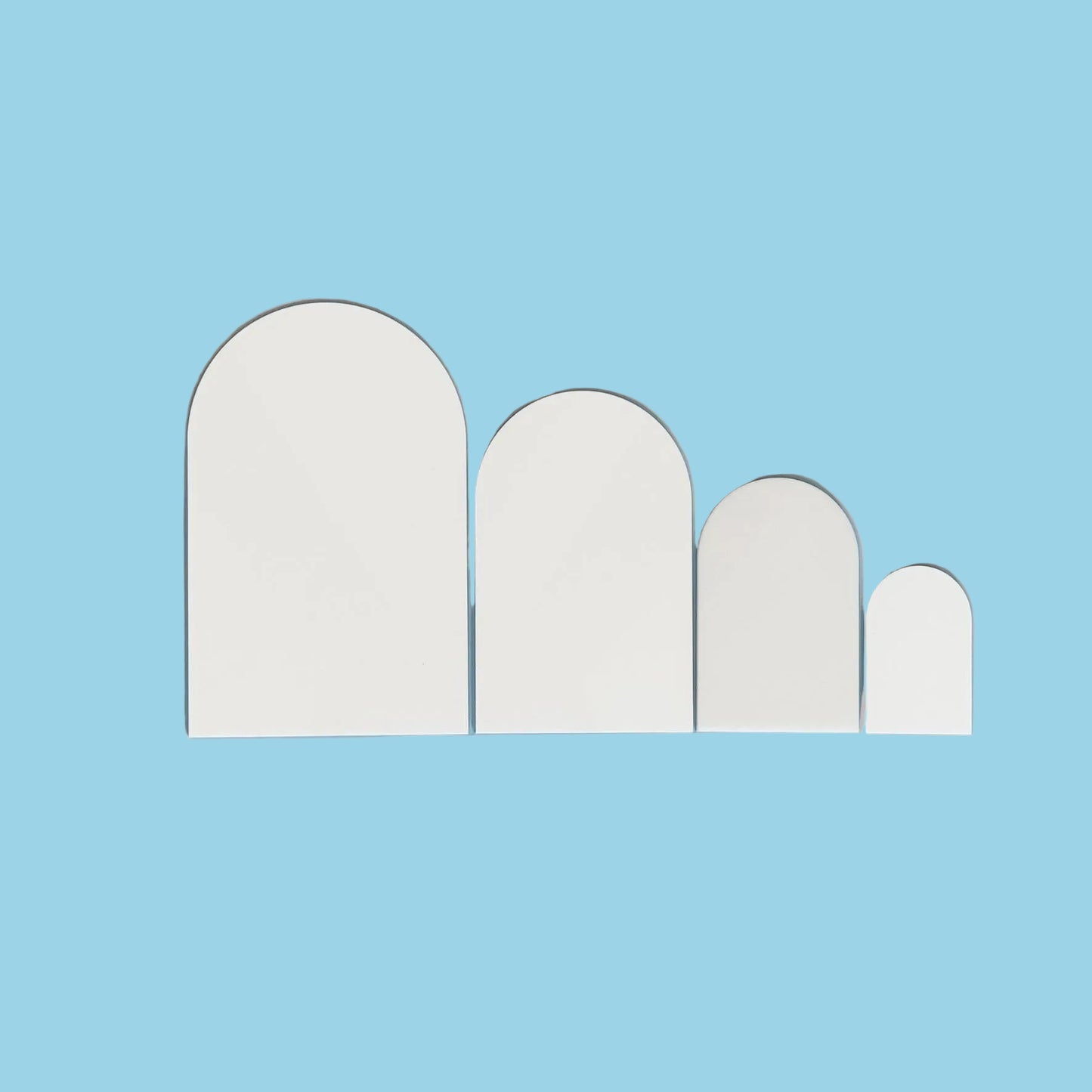 Set of four arch-shaped white acrylic cut outs on a light blue background
