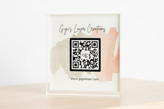 Framed artwork with a QR code and 'Gigi's Laser Creations' text on a white background