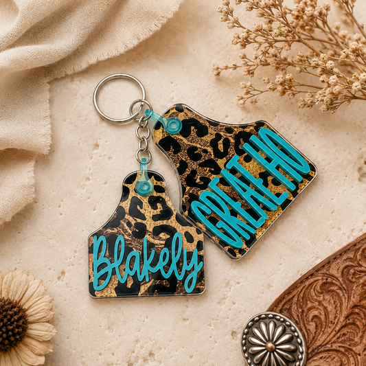 Leopard print keychain with 'Blakely' text on a beige surface with flowers and fabric.