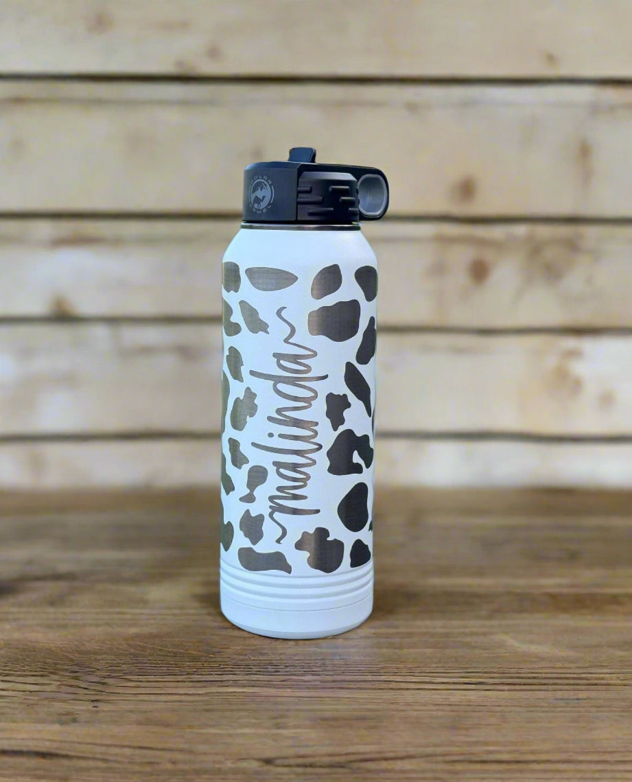 Engraved cow print water bottle close-up showing personalized name and pattern detail