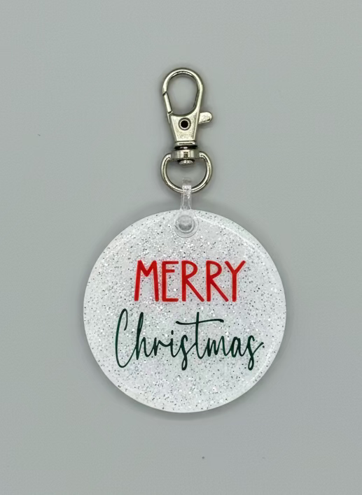 2" white glitter acrylic round keychain with Merry in red and Christmas in green.