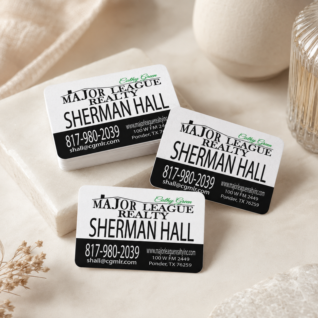 Three business cards for Major League Realty with contact information on a soft surface.