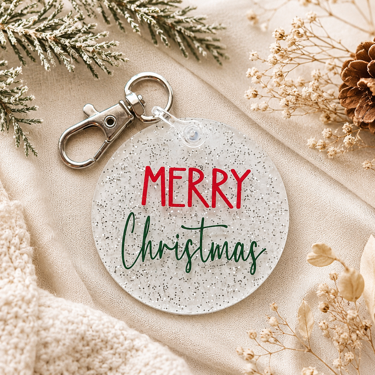 Round keychain with 'Merry Christmas' text on a beige surface with decorative elements.