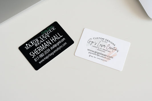 Two NFC enabled business cards on a textured surface, one black and one white.