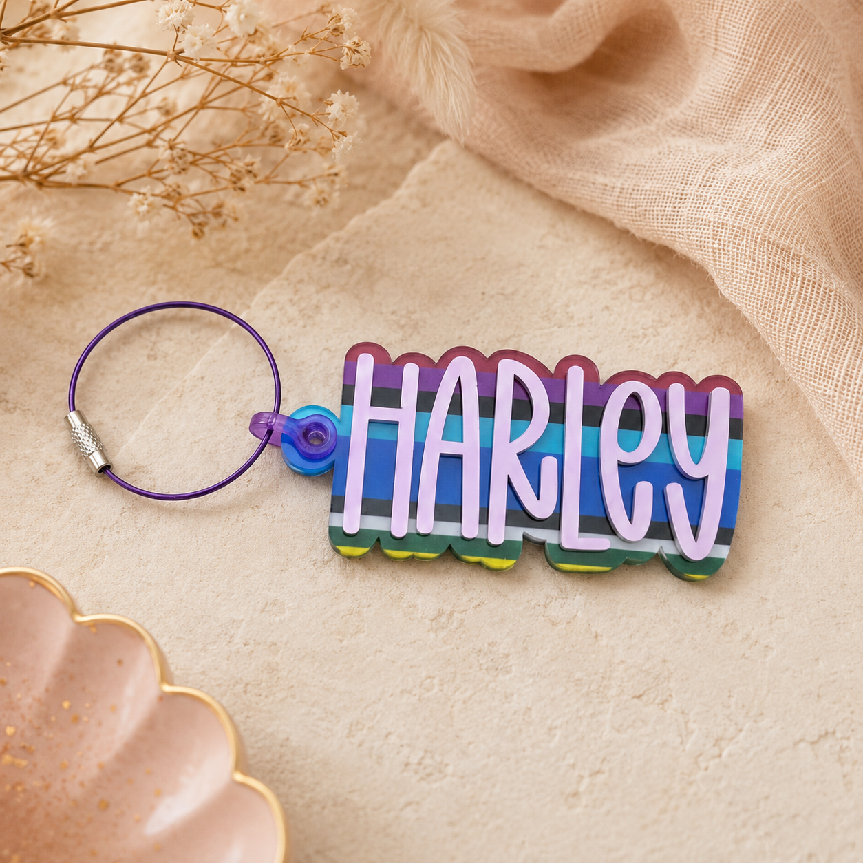 Colorful keychain with 'HARLEY' on a beige fabric background