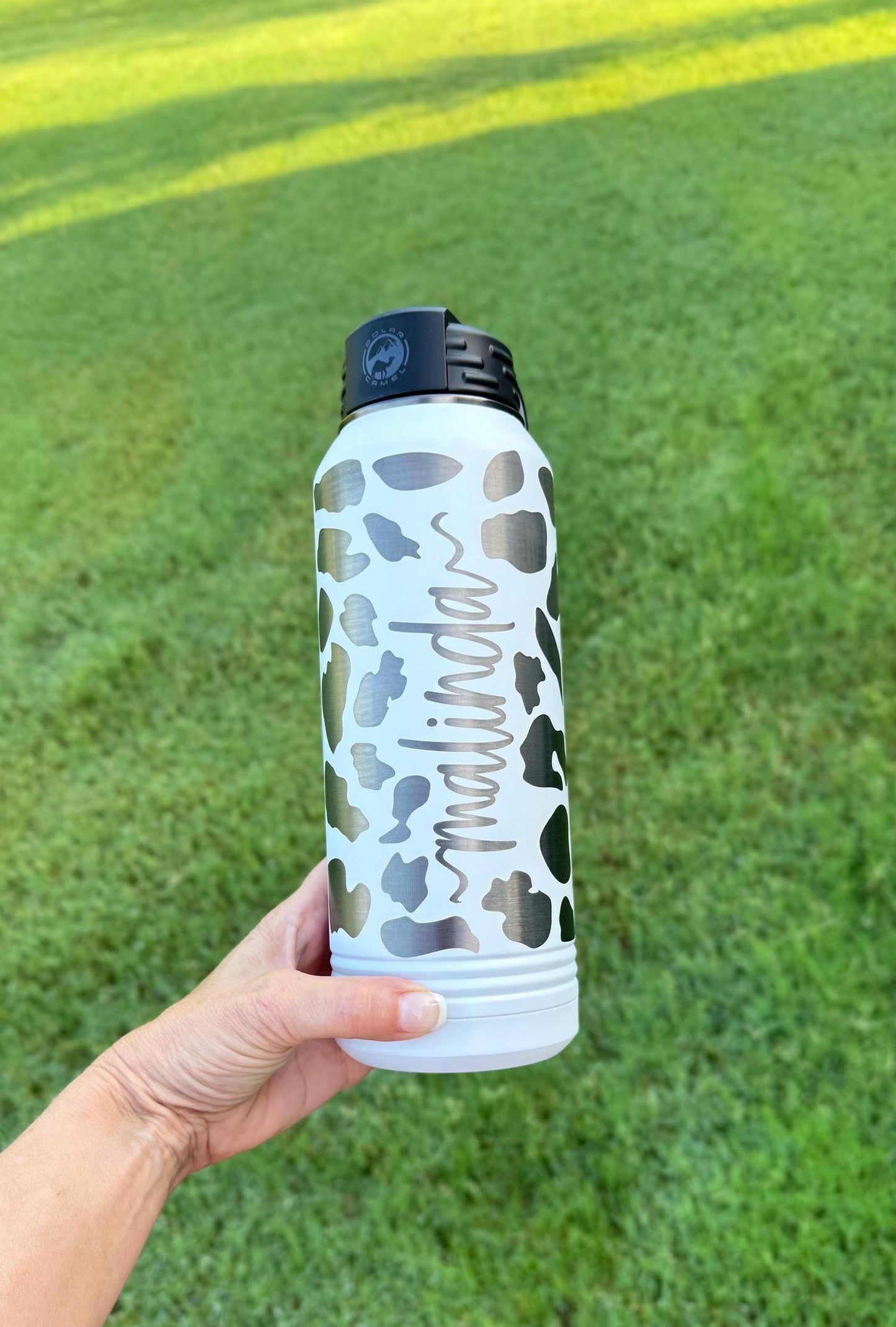 Personalized cow print water bottle displayed in lifestyle setting