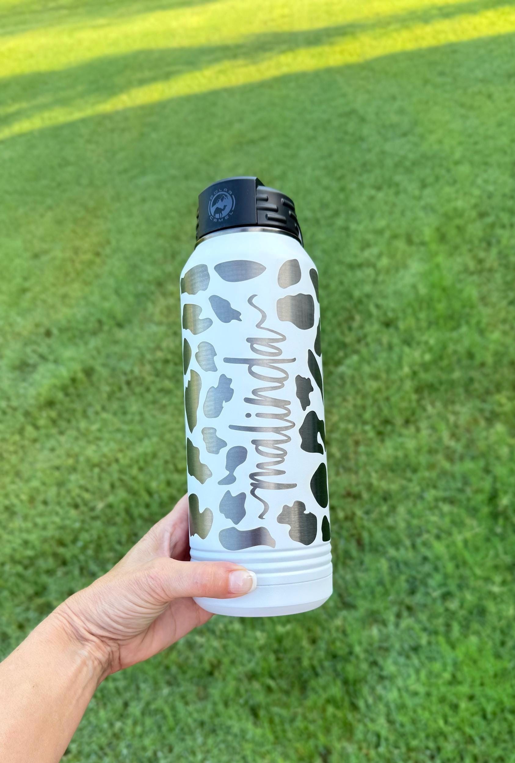 Personalized cow print water bottle displayed in lifestyle setting